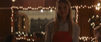Movie still from “Holiday Harmony” (2022), directed by Shaun Paul Piccinino – A woman standing in front of a window with lights in the background; Medium shot, Over the shoulder angle