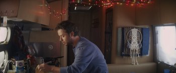 Movie still from “Holiday Harmony” (2022), directed by Shaun Paul Piccinino – A man is looking at a camera in a room; Medium shot, Low angle