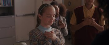Movie still from “Holiday Harmony” (2022), directed by Shaun Paul Piccinino – A young girl with her hands on her chest in prayer; Close Up shot, Over the shoulder angle