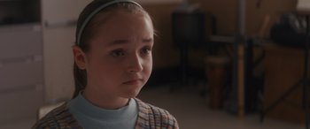 Movie still from “Holiday Harmony” (2022), directed by Shaun Paul Piccinino – A young girl wearing a blue headband looking at the camera; Close Up shot, Over the shoulder angle