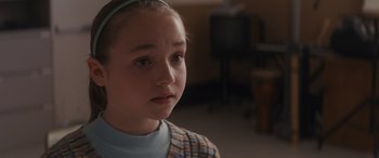 Movie still from “Holiday Harmony” (2022), directed by Shaun Paul Piccinino – A little girl with a blue headband is looking to her left; Close Up shot, Over the shoulder angle