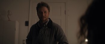 Movie still from “Holiday Harmony” (2022), directed by Shaun Paul Piccinino – A man standing in front of a white door; Close Up shot, Over the shoulder angle