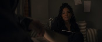 Movie still from “Holiday Harmony” (2022), directed by Shaun Paul Piccinino – A woman sitting on top of a couch holding a book; Close Up shot, Over the shoulder angle