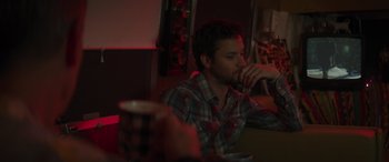 Movie still from “Holiday Harmony” (2022), directed by Shaun Paul Piccinino – A man sitting at a table with a drink in front of him; Medium shot, Over the shoulder angle