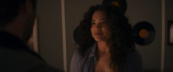 Movie still from “Holiday Harmony” (2022), directed by Shaun Paul Piccinino – A woman with curly black hair is standing in a room; Close Up shot, Over the shoulder angle