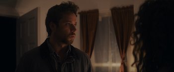 Movie still from “Holiday Harmony” (2022), directed by Shaun Paul Piccinino – A person in a dark room; Close Up shot, Over the shoulder angle