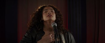 Movie still from “Holiday Harmony” (2022), directed by Shaun Paul Piccinino – A woman with her eyes closed holding a microphone in front of her face; Close Up shot, Over the shoulder angle