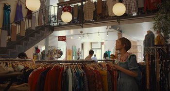 Movie still from “Hollywood Stargirl” (2022), directed by Julia Hart – A woman standing in front of clothes on a rack; Wide shot, Over the shoulder angle