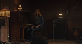 Movie still from “Hollywood Stargirl” (2022), directed by Julia Hart – A woman sitting in front of a piano in a dark room; Wide shot, Low angle