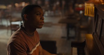 Movie still from “Hollywood Stargirl” (2022), directed by Julia Hart – A man sitting in front of a piano in a room; Close Up shot, Over the shoulder angle