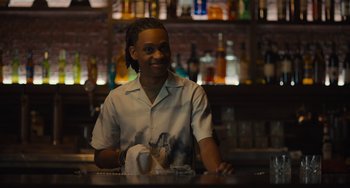 Movie still from “Hollywood Stargirl” (2022), directed by Julia Hart – A man sitting at a table with a drink in front of him; Medium shot, Over the shoulder angle
