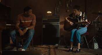 Movie still from “Hollywood Stargirl” (2022), directed by Julia Hart – A man and a woman sitting in front of an electric guitar; Medium shot, Over the shoulder angle