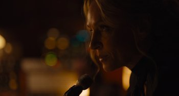 Movie still from “Hollywood Stargirl” (2022), directed by Julia Hart – A woman is speaking into a microphone in the dark; Close Up shot, Over the shoulder angle