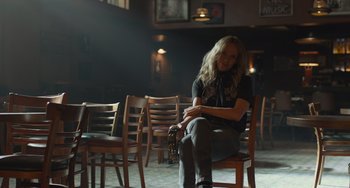 Movie still from “Hollywood Stargirl” (2022), directed by Julia Hart – A woman sitting on a wooden chair in a room; Medium shot, Low angle