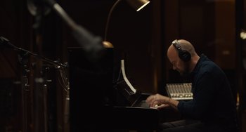 Movie still from “Hollywood Stargirl” (2022), directed by Julia Hart – A man sitting in front of a piano in a recording studio; Medium shot, High angle