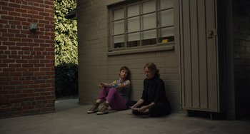 Movie still from “Hollywood Stargirl” (2022), directed by Julia Hart – Two women sitting on the ground in front of a brick building; Wide shot, High angle