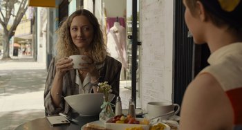 Movie still from “Hollywood Stargirl” (2022), directed by Julia Hart – A woman sitting at a table with a bowl of food; Medium shot, Over the shoulder angle