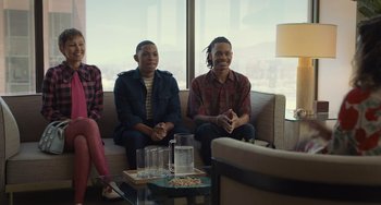 Movie still from “Hollywood Stargirl” (2022), directed by Julia Hart – Two men and a woman sitting on a couch in front of a window; Medium shot, Over the shoulder angle