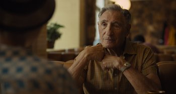 Movie still from “Hollywood Stargirl” (2022), directed by Julia Hart – An older man adjusting his tie while sitting in a chair; Close Up shot, Over the shoulder angle