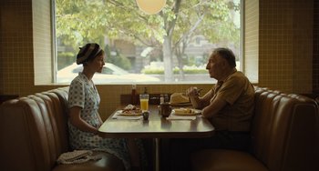 Movie still from “Hollywood Stargirl” (2022), directed by Julia Hart – An older man and a young woman sitting at a table; Medium shot, Over the shoulder angle