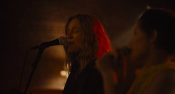 Movie still from “Hollywood Stargirl” (2022), directed by Julia Hart – A woman singing into a microphone in front of a crowd; Close Up shot, Low angle