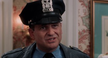Movie still from “Home Alone” (1990), directed by Chris Columbus – A police officer wearing a uniform and a hat; Close Up shot, Over the shoulder angle
