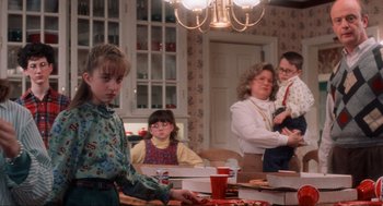 Movie still from “Home Alone” (1990), directed by Chris Columbus – A group of people sitting at a table with pizza; Medium shot, Over the shoulder angle