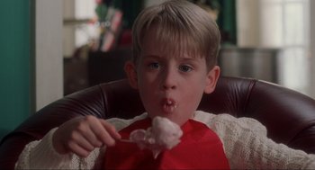 Movie still from “Home Alone” (1990), directed by Chris Columbus – A young boy is eating a piece of cake; Close Up shot, Low angle