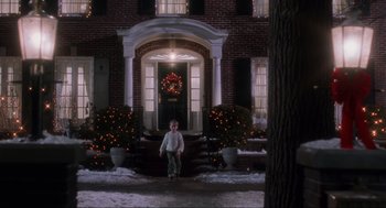 Movie still from “Home Alone” (1990), directed by Chris Columbus – A young boy riding a scooter in front of a house; Extreme Wide shot, Low angle