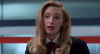 Movie still from “Home Alone” (1990), directed by Chris Columbus – A woman with blonde hair wearing a suit and red neck tie; Close Up shot, Low angle