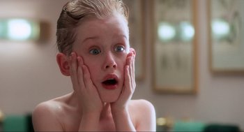 Movie still from “Home Alone” (1990), directed by Chris Columbus – A young boy is holding his hands up to his face; Close Up shot, Low angle
