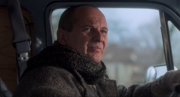 Movie still from “Home Alone” (1990), directed by Chris Columbus – A bald man wearing a coat and a scarf looking out a window; Close Up shot, Low angle