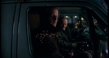Movie still from “Home Alone” (1990), directed by Chris Columbus – Two men sitting in the back seat of a car at night; Medium shot, Low angle