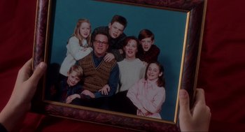Movie still from “Home Alone” (1990), directed by Chris Columbus – A person holding a framed picture of a family; Close Up shot, High angle