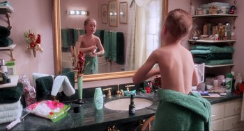 Movie still from “Home Alone” (1990), directed by Chris Columbus – A young boy is brushing his teeth in front of a mirror; Medium shot, High angle