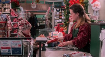 Movie still from “Home Alone” (1990), directed by Chris Columbus – A woman in a red shirt is handing a child some food at the checkout counter; Medium shot, High angle