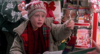Movie still from “Home Alone” (1990), directed by Chris Columbus – A young boy in a winter outfit holding a cell phone in his hand; Close Up shot, High angle