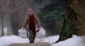 Movie still from “Home Alone” (1990), directed by Chris Columbus – A young boy carrying two bags of garbage; Wide shot, Low angle