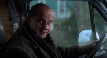 Movie still from “Home Alone” (1990), directed by Chris Columbus – A man sitting in the back seat of a car wearing a scarf; Close Up shot, Low angle