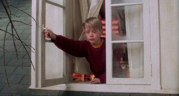 Movie still from “Home Alone” (1990), directed by Chris Columbus – A young boy looking out of a window; Medium shot, Low angle