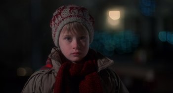 Movie still from “Home Alone” (1990), directed by Chris Columbus – A young boy wearing a winter hat and scarf in front of a full moon; Close Up shot, Low angle