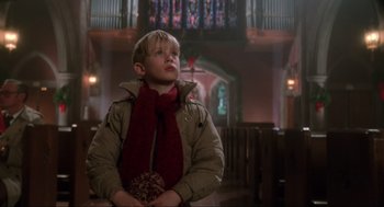 Movie still from “Home Alone” (1990), directed by Chris Columbus – A young boy in a jacket and a scarf in a church; Medium shot, Low angle