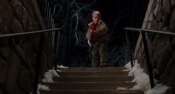 Movie still from “Home Alone” (1990), directed by Chris Columbus – A young boy walking up some steps in the snow; Wide shot, High angle