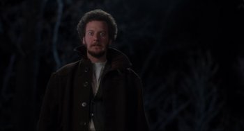 Movie still from “Home Alone” (1990), directed by Chris Columbus – A man wearing a brown coat standing in the dark; Medium shot, Low angle
