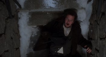 Movie still from “Home Alone” (1990), directed by Chris Columbus – A man with a beard and a jacket is in the snow; Medium shot, Overhead angle