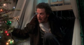 Movie still from “Home Alone” (1990), directed by Chris Columbus – A man sitting on the ground wearing a brown coat; Medium shot, Low angle