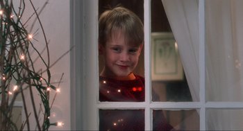 Movie still from “Home Alone” (1990), directed by Chris Columbus – A young boy looking out of a window at christmas; Close Up shot, Low angle