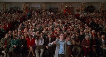 Movie still from “Home Alone 2: Lost in New York” (1992), directed by Chris Columbus – A crowd of people sitting in front of a man; Extreme Wide shot, High angle
