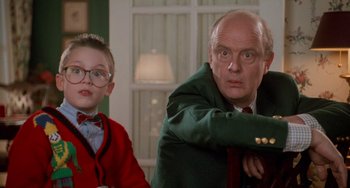 Movie still from “Home Alone 2: Lost in New York” (1992), directed by Chris Columbus – A man and a boy are standing next to each other in a room; Close Up shot, Low angle