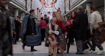 Movie still from “Home Alone 2: Lost in New York” (1992), directed by Chris Columbus – A young boy holding a bag in a crowd of people; Wide shot, High angle